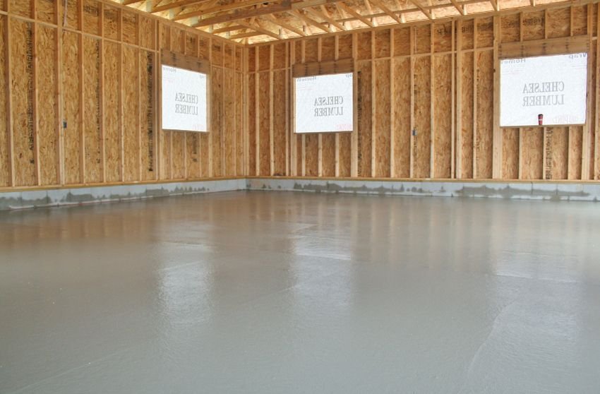 Empty unfinished room with exposed wood framing and a smooth gray concrete floor