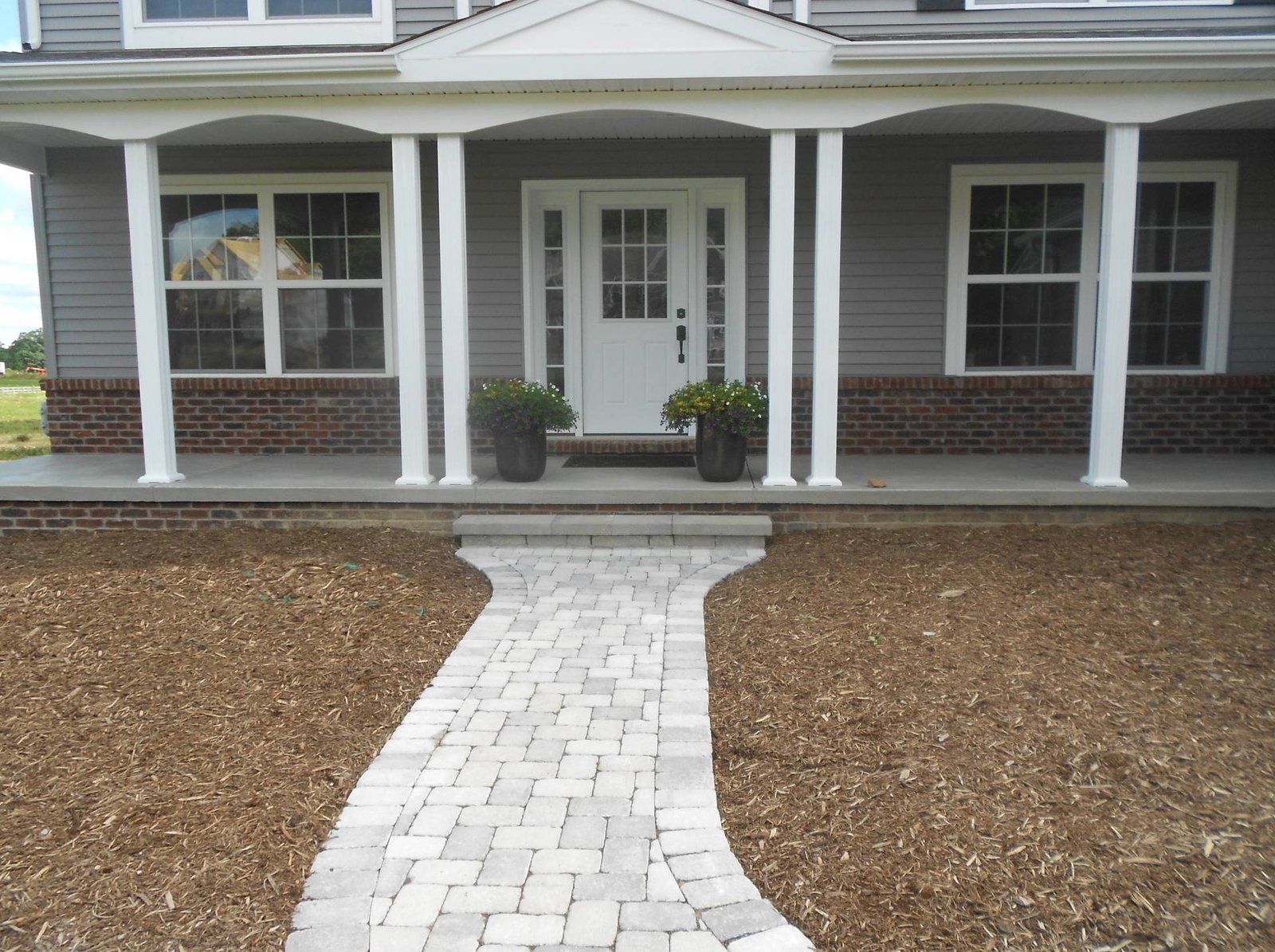 Front porch of a house with white columns and a stone walkway leading to the entrance.