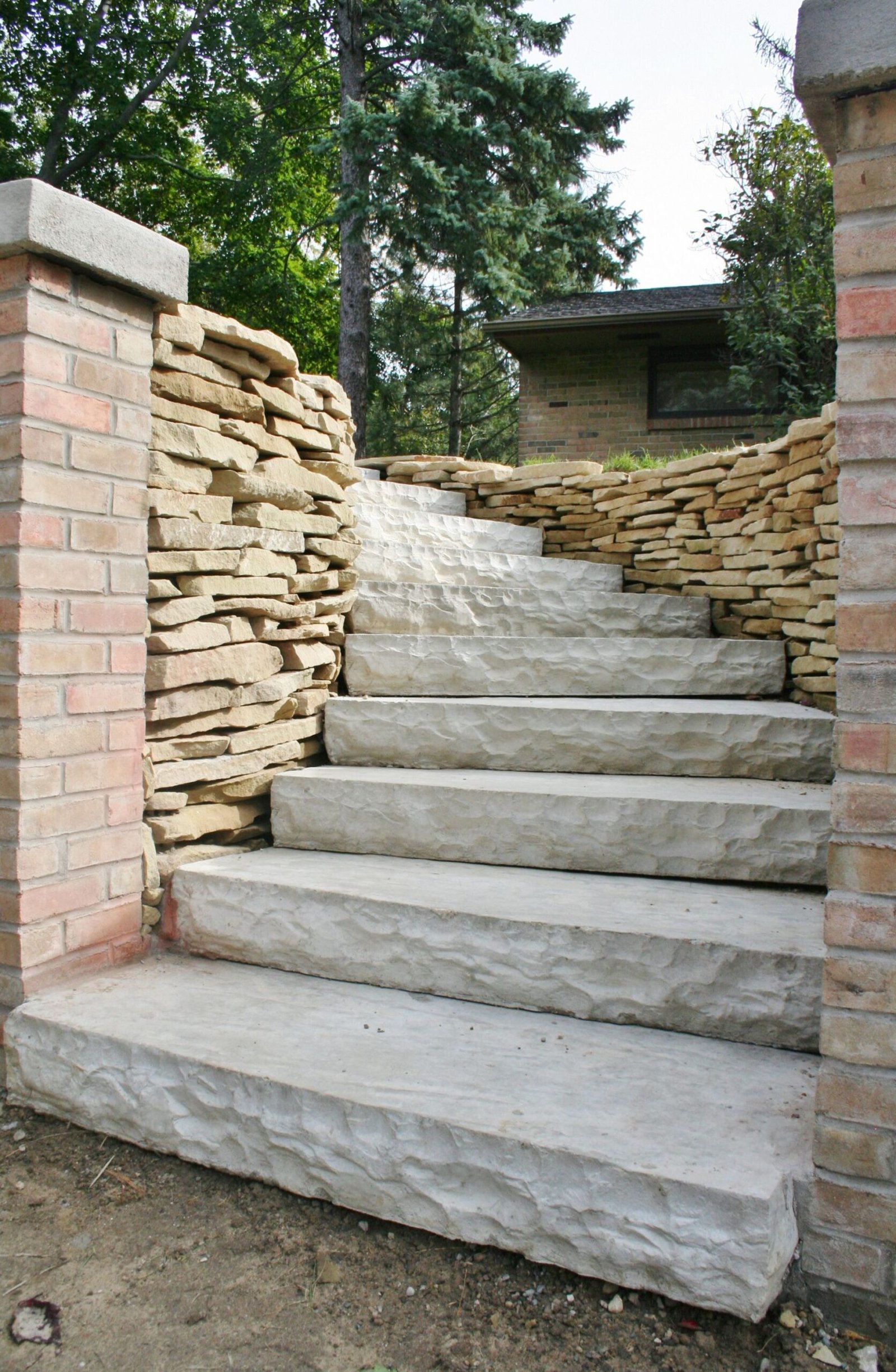 Stone staircase ascending between brick and stone walls in a garden or courtyard