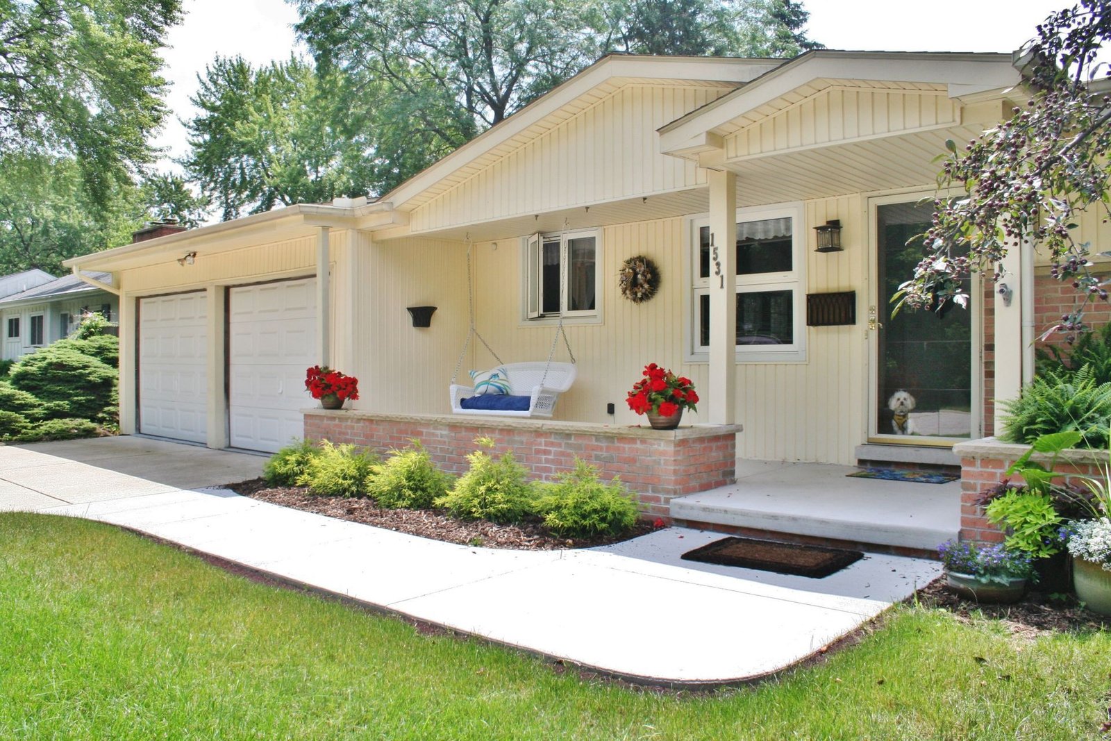 Cream house with front porch, garage, and curved white walkway