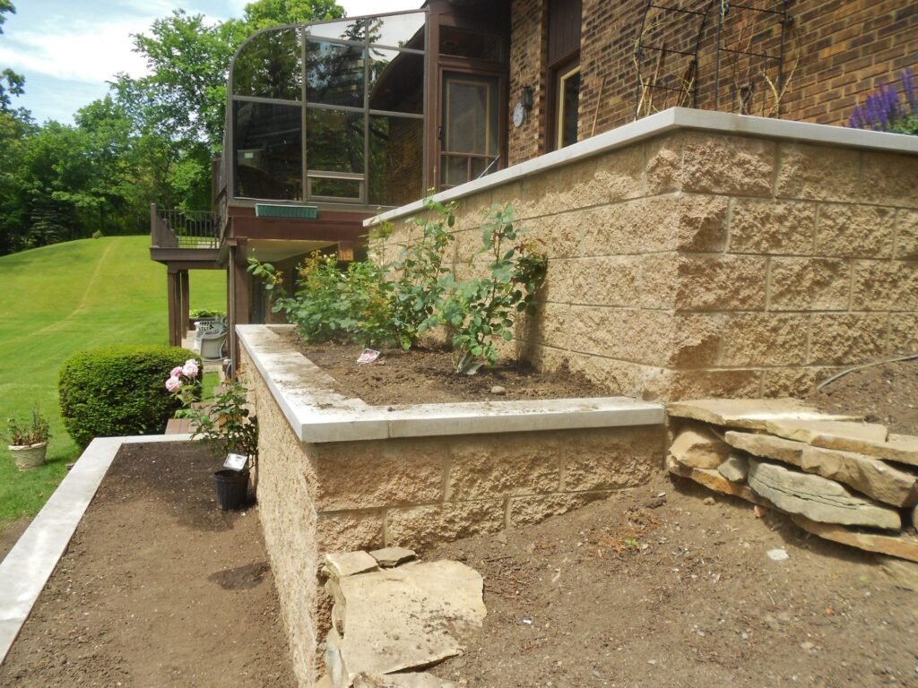 Tiered stone-face retaining wall with planting beds at a home in Ann Arbor, MI