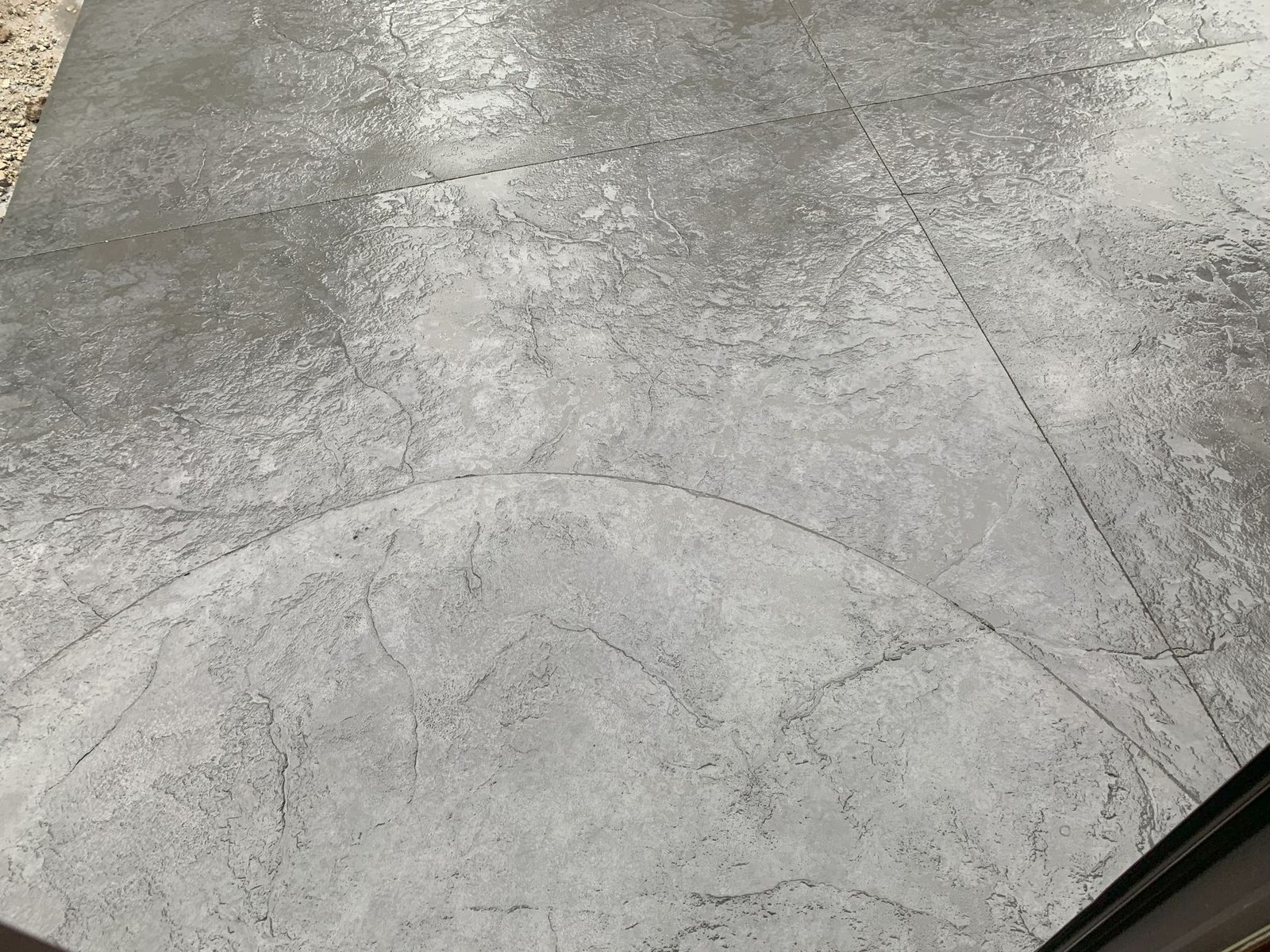 Close-up of a gray concrete sidewalk with faint circular and diagonal seams