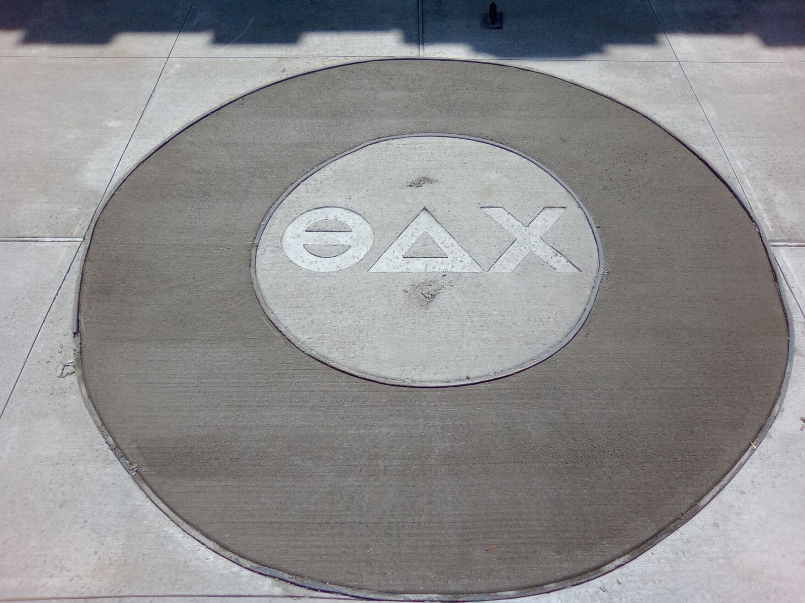 PlayStation button logo on a circular pavement marker with triangle, circle, X, and square symbols