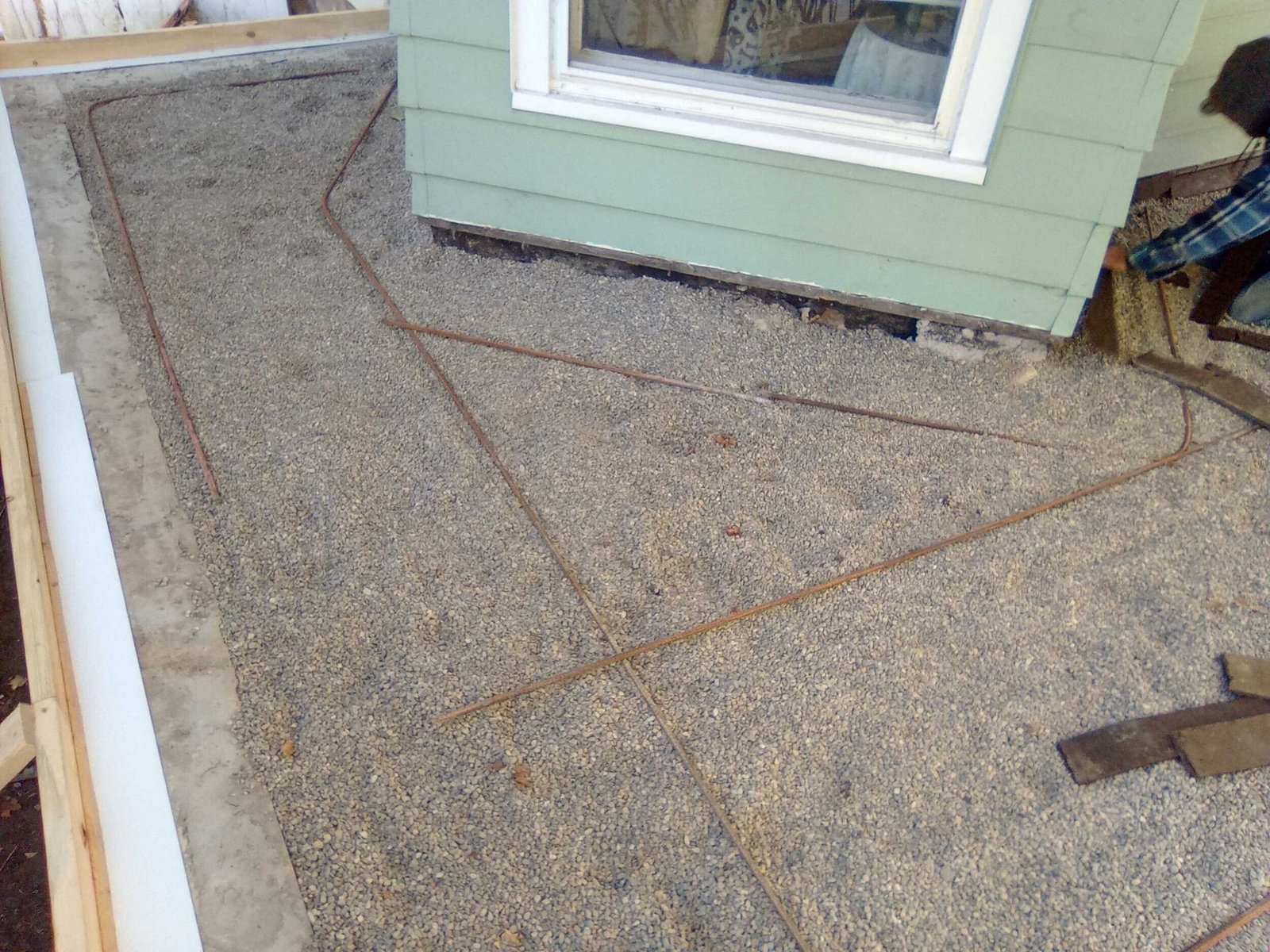 Roofing underlayment on a sloped roof beside a green house wall and window