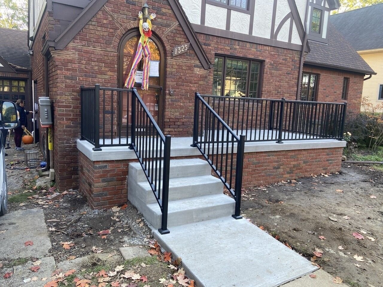 Brick house with front steps, black railings, and a wheelchair ramp leading to the porch.