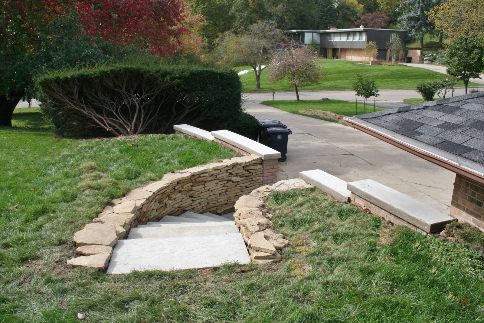 Collapsed sidewalk section beside a curb and retaining wall in Ann Arbor, MI